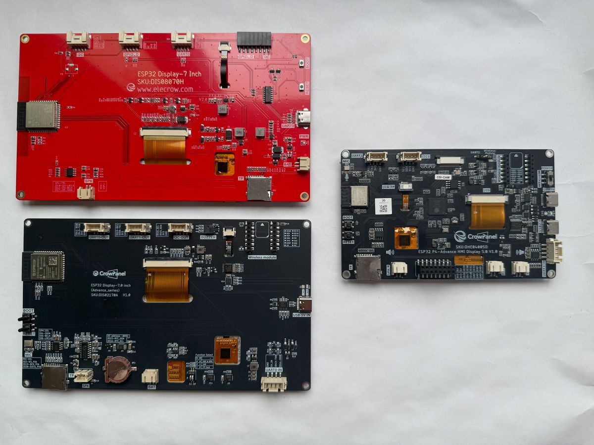 The three Elecrow CrowPanel generations side by side on a desk: the CrowPanel 7.0, the Advance 7.0 and the smaller Advance 5.0 ESP32-P4